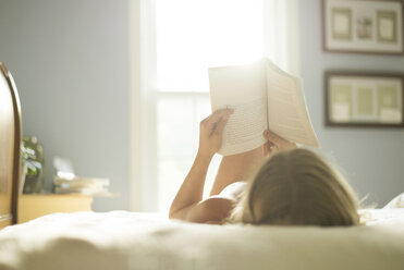 Caucasian girl reading book on bed - BLEF06254