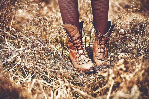 Boots of Caucasian teenage girl standing in tall grass - BLEF06321