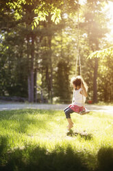 Girl sitting on swing in field - BLEF06360