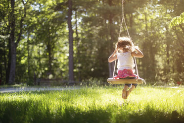 Girl sitting on swing in field - BLEF06361