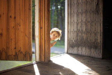 Curious girl peering around open door - BLEF06372