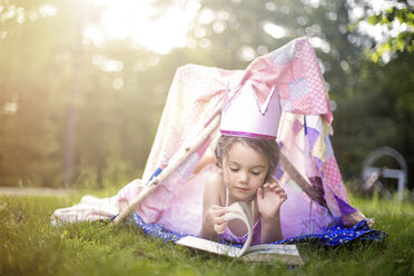 Girl reading in tent in backyard - BLEF06380