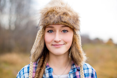 Kaukasisches Teenager-Mädchen mit Pelzmütze auf einem Feld - BLEF06397