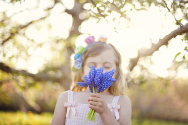 Caucasian girl smelling flowers outdoors - BLEF06410