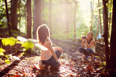 Caucasian girl photographing sister in forest - BLEF06422