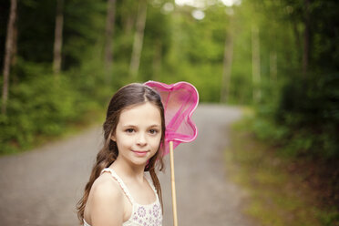 Caucasian girl carrying butterfly net on dirt road - BLEF06425