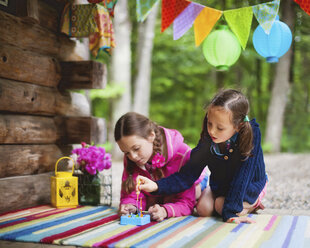 Kaukasische Mädchen spielen mit Spielzeug auf einer Hüttenveranda - BLEF06439