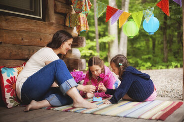 Kaukasische Mutter und Töchter spielen mit Spielzeug auf einer Veranda - BLEF06440