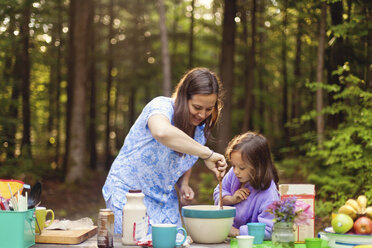 Caucasian mother and daughter cooking in forest - BLEF06441