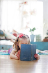 Mädchen liest ein Buch auf dem Boden im Wohnzimmer - BLEF06445