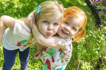 Caucasian sisters hugging in backyard - BLEF06452