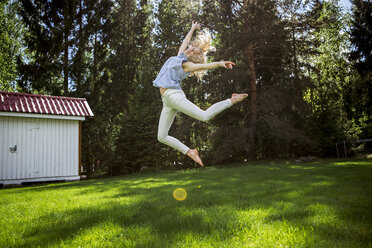 Frau springt vor Freude im Hinterhof - BLEF06455