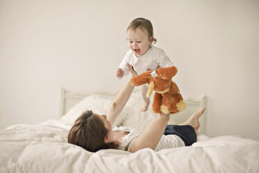 Caucasian mother playing with baby on bed - BLEF06460