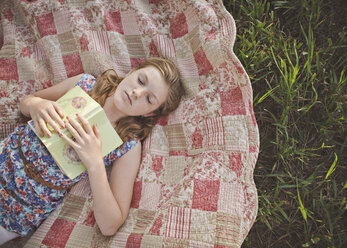 Caucasian girl sleeping with book on blanket - BLEF06465