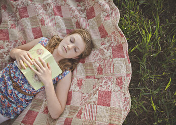 Kaukasisches Mädchen schlafend mit Buch auf Decke - BLEF06465