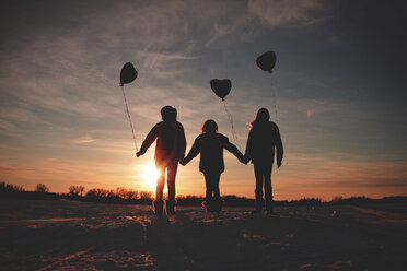 Caucasian girls walking with balloons at sunset - BLEF06470