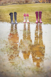 Reflexion von Menschen aus Regenstiefeln in einer Pfütze - BLEF06471