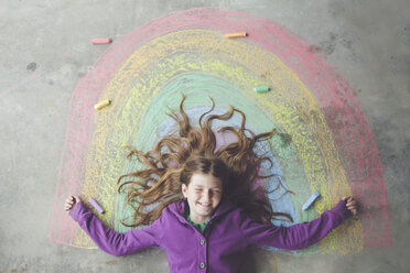 Caucasian girl laying on chalk rainbow - BLEF06474