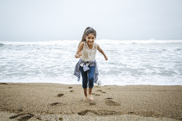 Hispanic girl walking barefoot on beach - BLEF06482