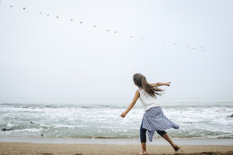 Hispanisches Mädchen spielt am Strand, lizenzfreies Stockfoto