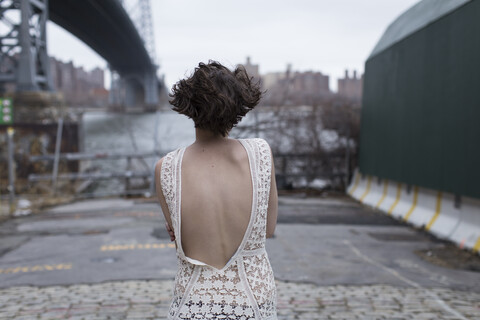 Frau in tief ausgeschnittenem Kleid zu Fuß im Industriegebiet, lizenzfreies Stockfoto
