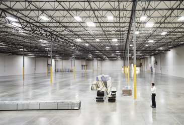 Caucasian businessman standing in empty warehouse - BLEF06561