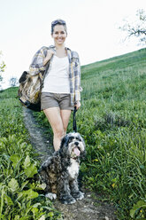 Caucasian woman walking dog on grassy hillside - BLEF06588