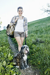 Kaukasische Frau geht mit Hund auf grasbewachsenem Hügel spazieren - BLEF06588