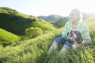 Older Caucasian woman walking dog on grassy hillside - BLEF06589