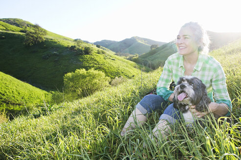 Ältere kaukasische Frau führt Hund auf grasbewachsenem Hügel aus - BLEF06589