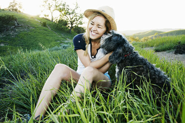 Caucasian woman petting dog in field - BLEF06595