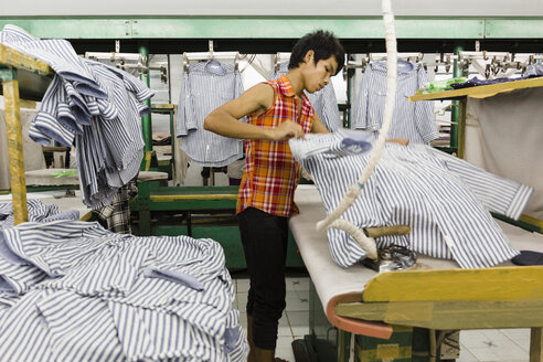 Asiatischer Arbeiter bügelt Hemd in Bekleidungsfabrik - BLEF06606