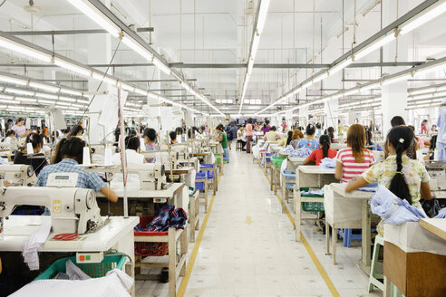 Asiatische Arbeiterin näht Kleidung in einer Bekleidungsfabrik - BLEF06607