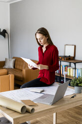 Frau im Büro hält Papier mit Windradmodell auf dem Tisch - GIOF06396