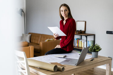 Frau im Büro hält Papier mit Windradmodell auf dem Tisch - GIOF06398