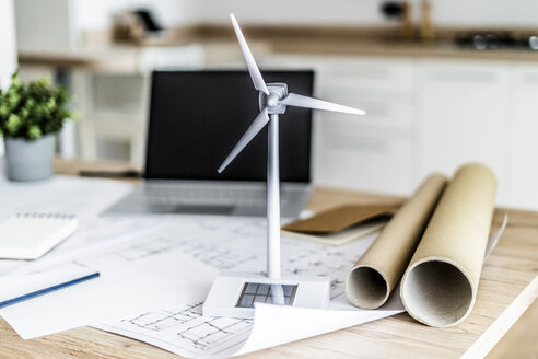 Modell einer Windkraftanlage, Bauplan und Laptop auf einem Tisch im Büro - GIOF06405