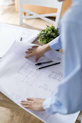 Close-up of woman in office working on plan on table - GIOF06420