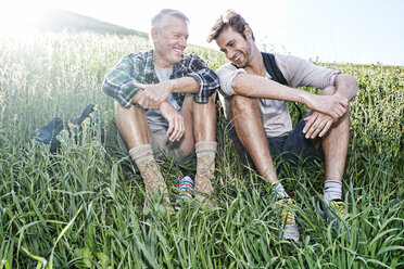 Kaukasischer Vater und Sohn sitzen auf einem grasbewachsenen Hügel - BLEF06645