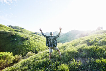 Older Caucasian man cheering on rural hillside - BLEF06651