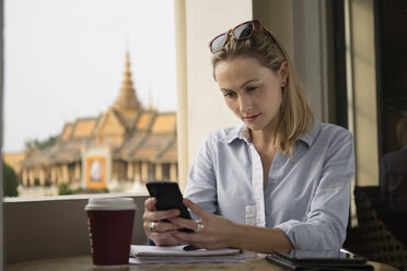 Caucasian businesswoman using cell phone in cafe, Phnom Penh, Cambodia - BLEF06663