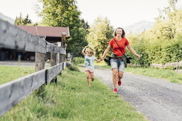 Glückliche Mutter und Tochter beim Laufen auf einem Feldweg, Jochberg, Österreich - PSIF00277