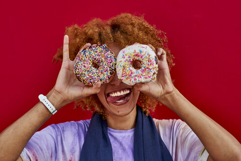 Playful woman holding two donuts in front of her eyes - VEGF00282