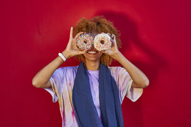 Playful woman holding two donuts in front of her eyes - VEGF00283