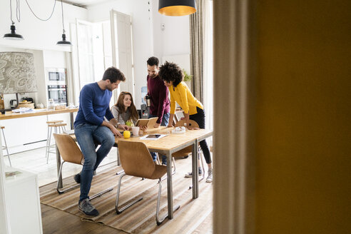 Four friends in dining room at home with book - GIOF06443