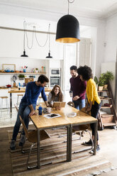 Four friends in dining room at home with book - GIOF06444