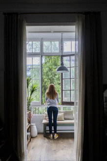 Rückansicht einer jungen Frau zu Hause, die aus dem Fenster schaut - GIOF06482