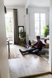 Verliebtes Paar mit Laptop, das sich zu Hause auf dem Boden entspannt - GIOF06491