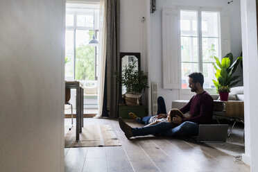 Verliebtes Paar mit Laptop, das sich zu Hause auf dem Boden entspannt - GIOF06492