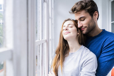 Lächelndes, zärtliches Paar am Fenster zu Hause - GIOF06497