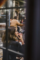 Young woman with camera in a bar at night - LJF00095